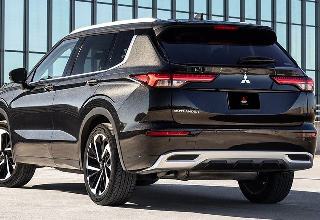 Metallic black Mitsubishi Outlander, parked outdoors with a modern glass office building structure